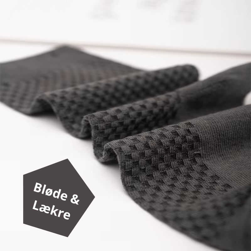 Fire sorte bambusstrømper foldet og lagt ved siden af hinanden med synlig ternede rillestruktur og teksten "Bløde & Lækre" – naturligt bløde og hudvenlige herrestrømper i bambusviskose str. 38-45 – Bambusstrømper til mænd | BIBAMBUS 'The Bamboo Gentleman'