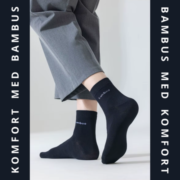 Sorte bambus strømper med hvid bamboo-tekst båret på begge fødder under grå bukser – lifestyle-foto med mørk grafisk ramme – Bambus strømper | BIBAMBUS 'Lovely Bamboo Feet'
