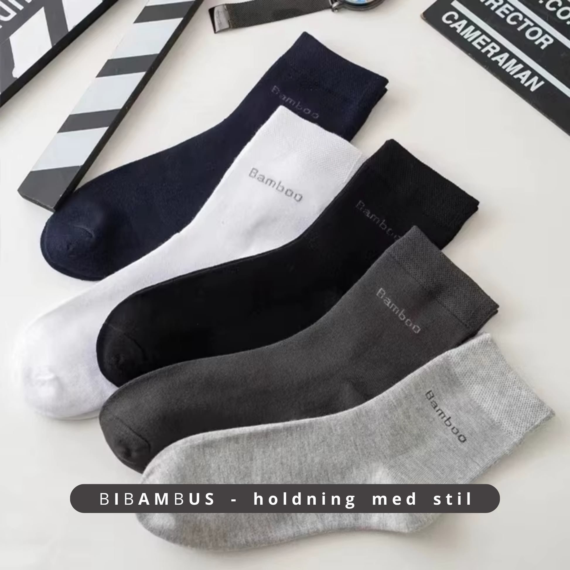  Fem par bambus strømper i navy, hvid, sort, mørkegrå og lysegrå lagt ud på hvid flade med filmrekvisitter i baggrunden – Bambus strømper | BIBAMBUS 'Lovely Bamboo Feet'