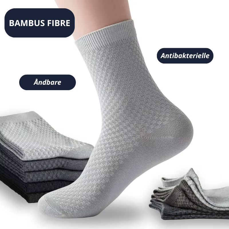 Lysegrå bambusstrømpe med ternede rillestruktur i forgrunden med tekst-badges: Bambus Fibre, Åndbare og Antibakterielle – foldede strømper i grå og sorte nuancer i baggrunden – Bambusstrømper til mænd | BIBAMBUS 'The Bamboo Gentleman'