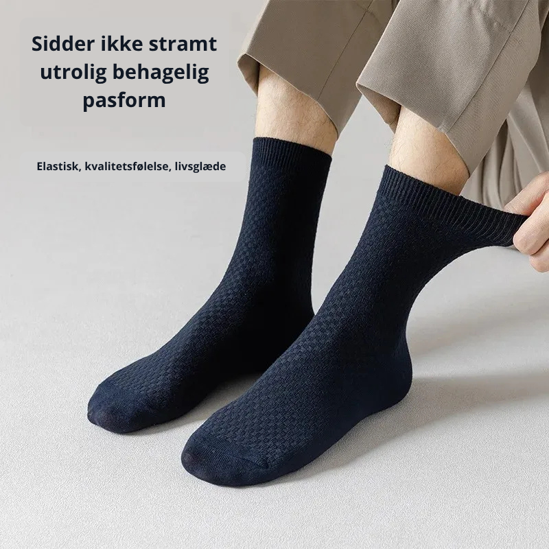 Mand der tager marineblå bambusstrømper på med teksten "Sidder ikke stramt – utrolig behagelig pasform" og "Elastisk, kvalitetsfølelse, livsglæde" – åndbare og hudvenlige herrestrømper i bambusviskose str. 38-45 – Bambusstrømper til mænd | BIBAMBUS 'The Bamboo Gentleman'