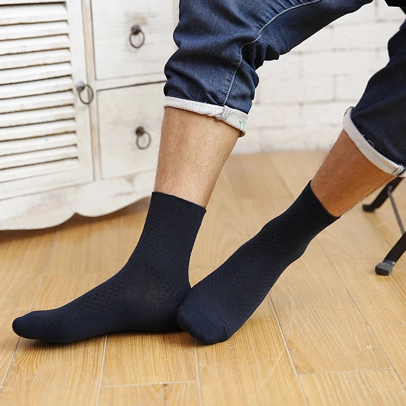 Mand i opsmøgede mørkeblå jeans iført marineblå bambusstrømper på træ gulv foran hvidt vintage skab – afslappet og stilfuld hverdagslook med åndbare herrestrømper i bambusviskose str. 38-45 – Bambusstrømper til mænd | BIBAMBUS 'The Bamboo Gentleman'