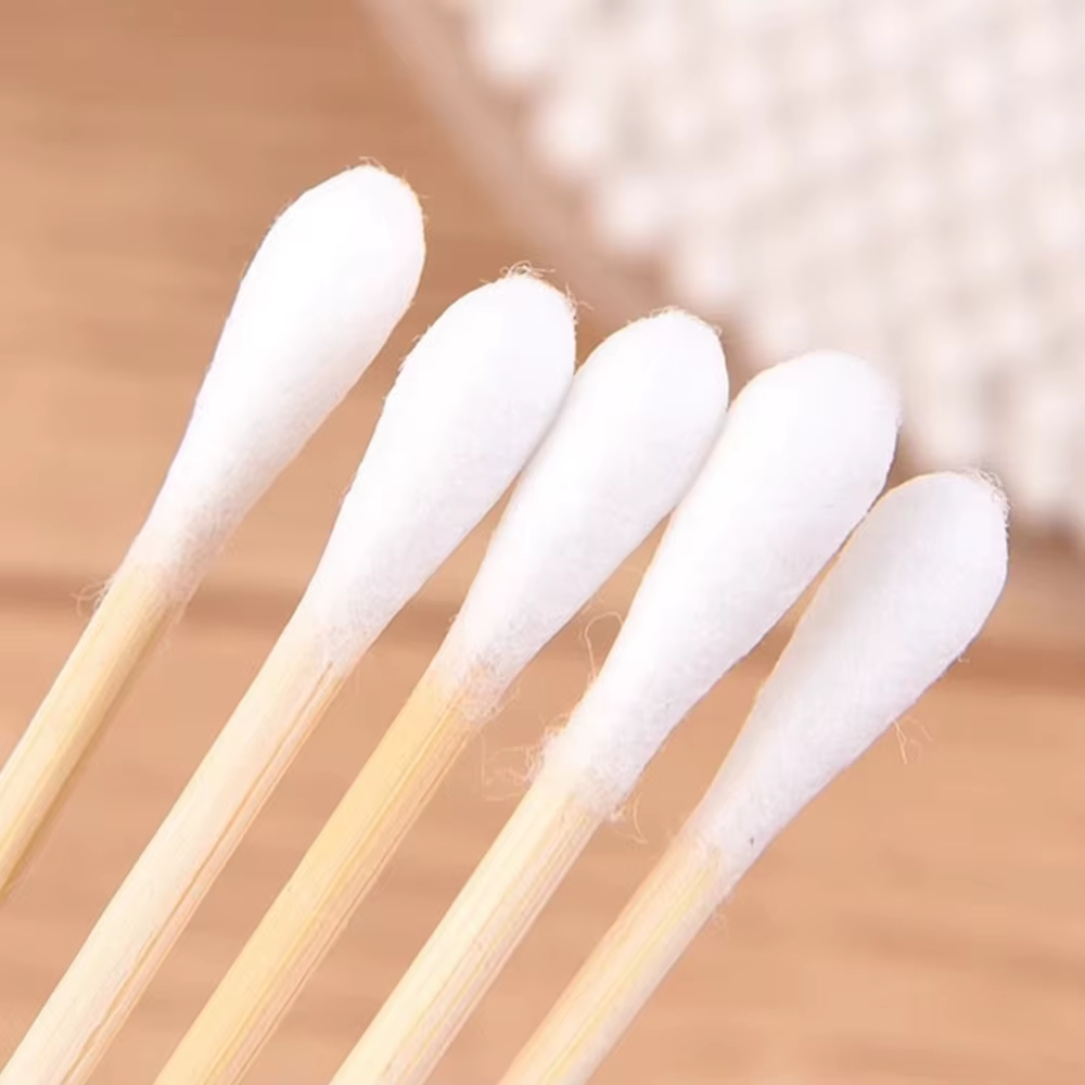 Nærbillede af bambus ørepinde med blød hvid bomuld på naturligt træbord – Bambus Ørepinde | BIBAMBUS 'Clean Cotton Bamboo'