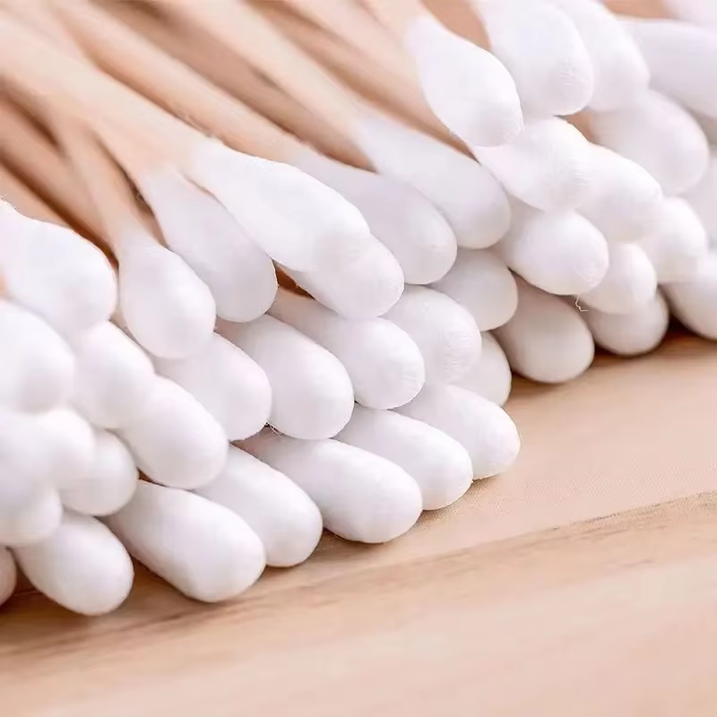 Nærbillede af række hvide bomuld-ender på bambus ørepinde på træbord – Bambus Ørepinde | BIBAMBUS 'Clean Cotton Bamboo'