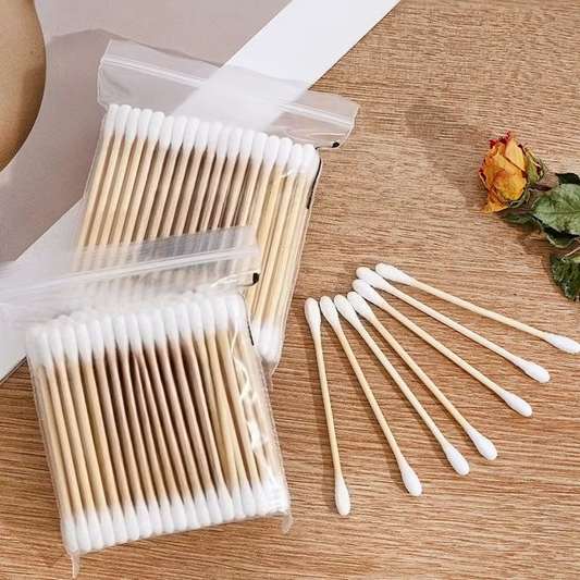 Bambus ørepinde i gennemsigtige poser på træbord med tørret rose – Bambus Ørepinde | BIBAMBUS 'Clean Cotton Bamboo'